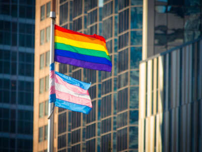 Transgender and LGBTQ pride flags fly in front of buildings
