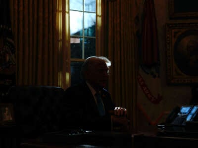Donald Trump sits in a darkened oval office