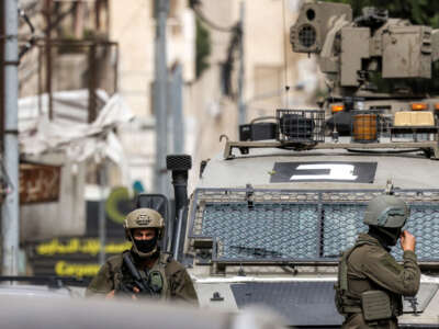 Israeli army soldiers stand outside an armored vehicle during an Israeli military operation in Nablus in the occupied West Bank on April 8, 2025.