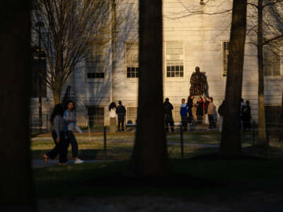 People gather to take photos with the John Harvard Statue at Harvard University on April 17, 2025, in Cambridge, Massachusetts.